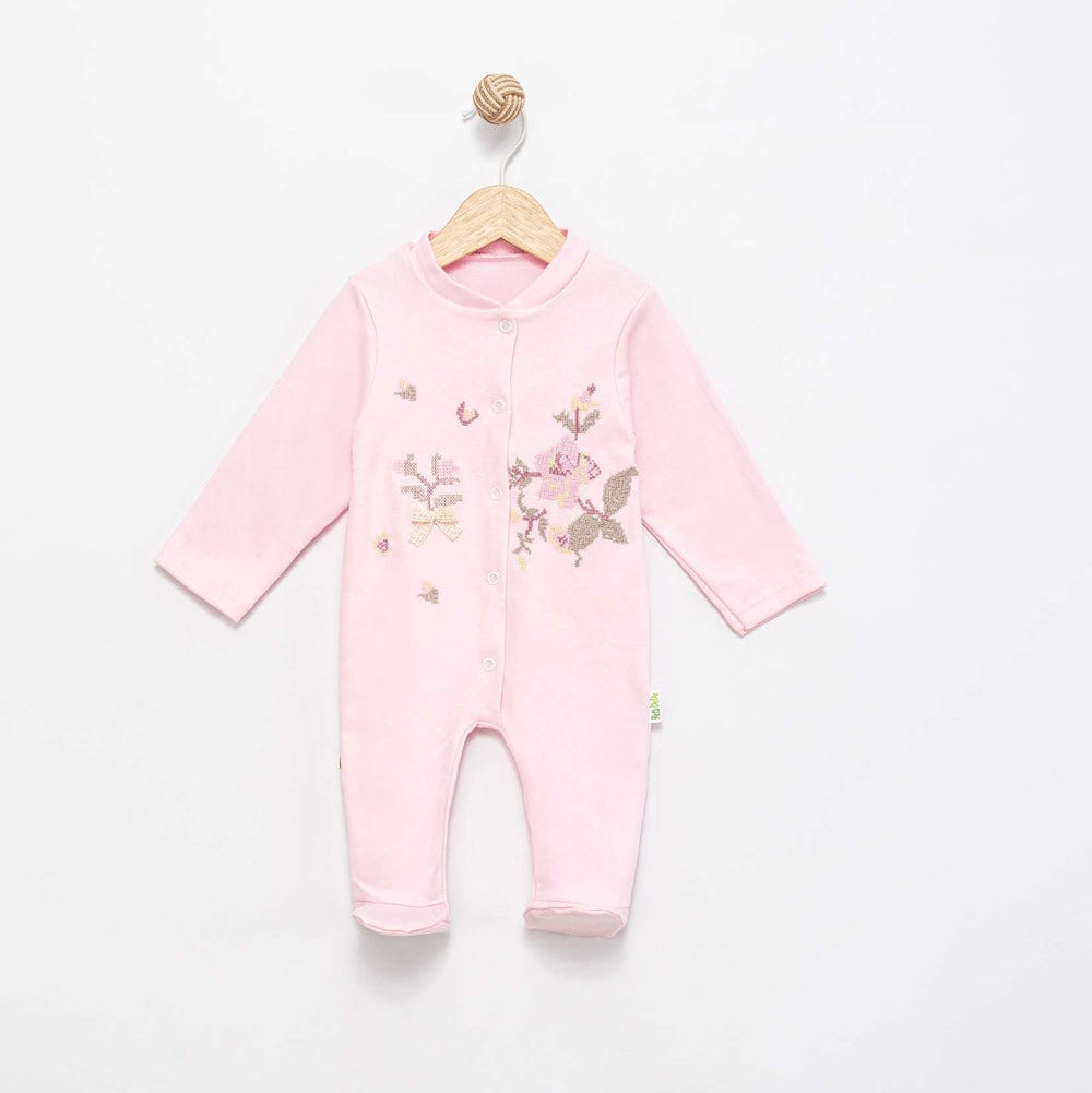 A light pink long-sleeve baby footless one-piece jumpsuit with embroidered floral and butterfly details on the front, hanging on a wooden hanger against a plain white wall.