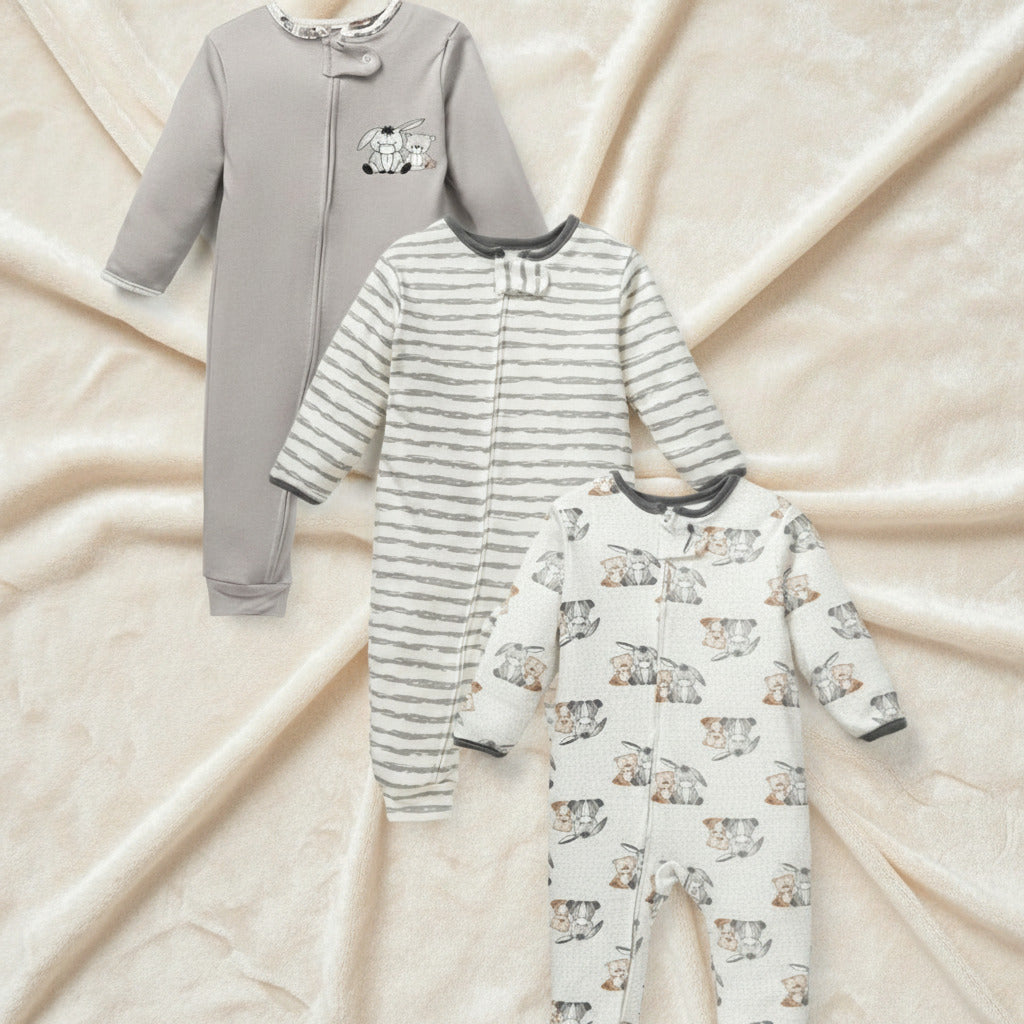 Three baby footed sleepers laid out on a white background: one solid light gray, one gray and white striped, and one white with a gray and beige cat print.