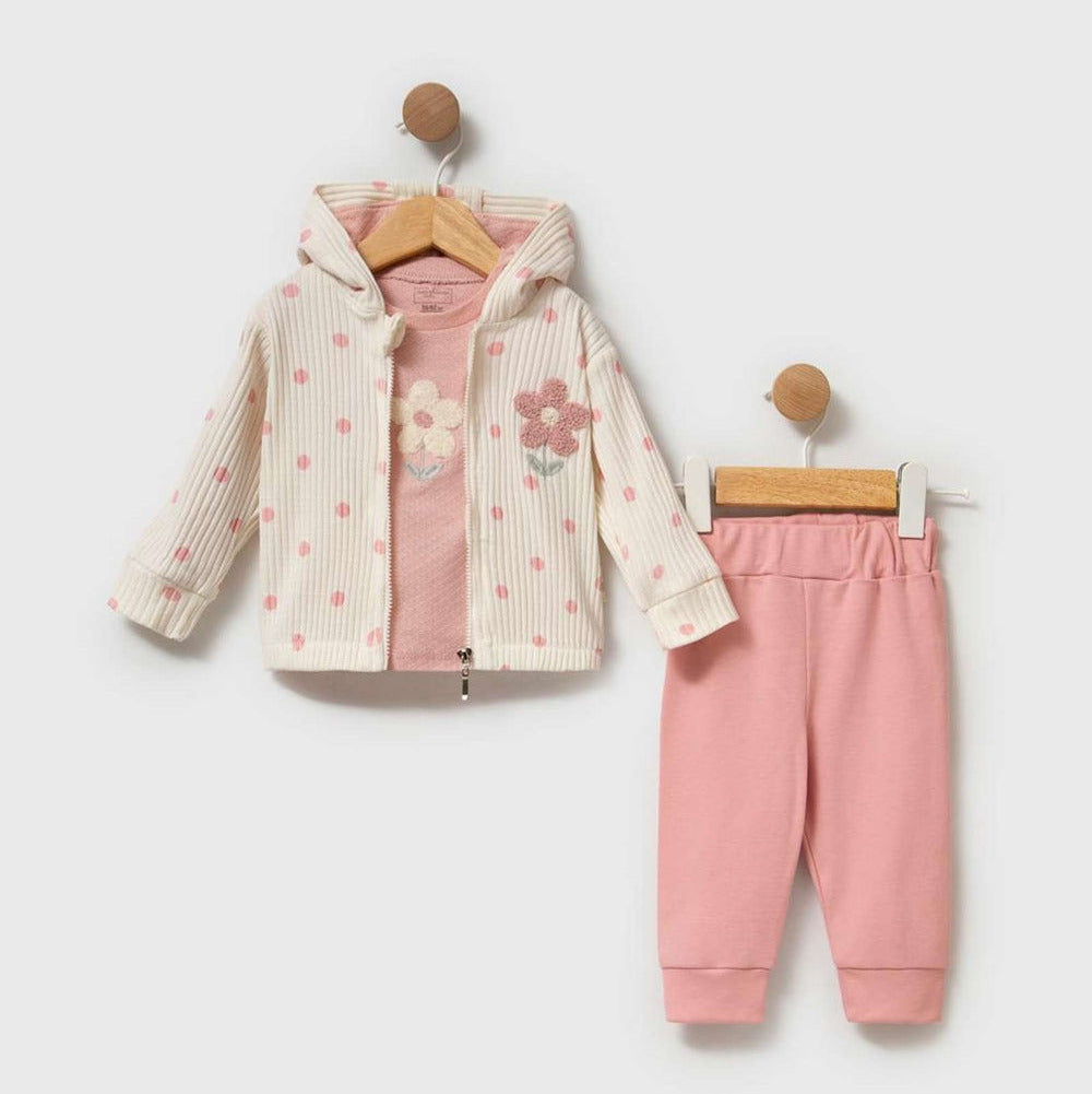 A toddler girl's two-piece clothing set hanging on wooden hangers against a light gray background. The set includes a hooded zip-up jacket in off-white with pink polka dots and a pink floral applique on the chest, paired with matching pink jogger pants.