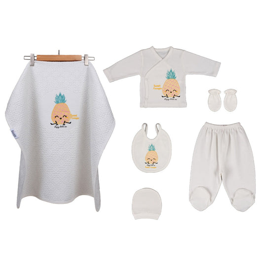 A baby clothing and textile set laid out on a white background, including a white waffle-knit bib, a white long-sleeve top, white footed pants, white mittens, a white beanie, and a white muslin wrap with a pineapple graphic.