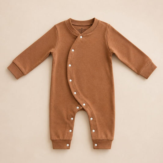 A long-sleeve baby romper in a warm camel brown color, featuring a snap-button closure down the front and on the legs, laid flat on a light beige background.