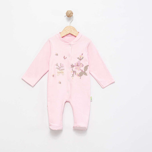 A light pink long-sleeve baby footless one-piece jumpsuit with embroidered floral and butterfly details on the front, hanging on a wooden hanger against a plain white wall.