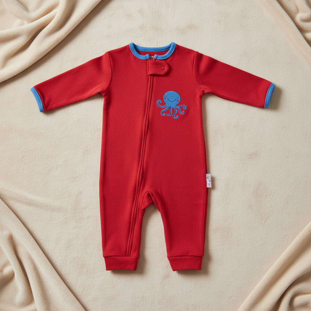 Three baby long-sleeve footless one-piece sleepers shown side by side on a white background: a white sleeper with pink flamingo print, a red sleeper with blue trim and a blue octopus graphic, and a blue sleeper with a subtle blue pattern.