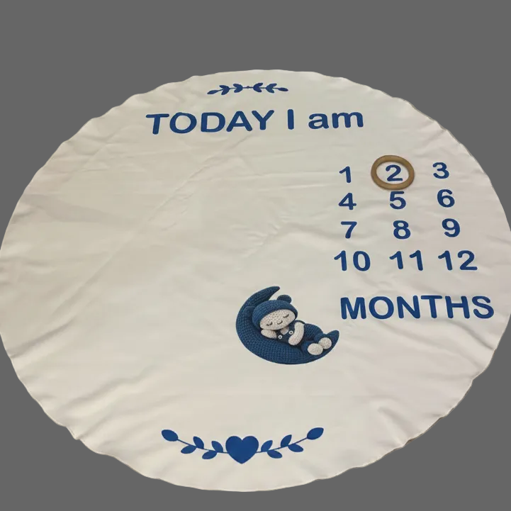 A round white baby milestone rug laid on a beige tiled floor. The rug features blue text reading 'TODAY I am' and 'MONTHS' with a numbered age tracker from 1 to 12, a small cartoon baby sleeping on a crescent moon, and blue decorative leaf and heart motifs.