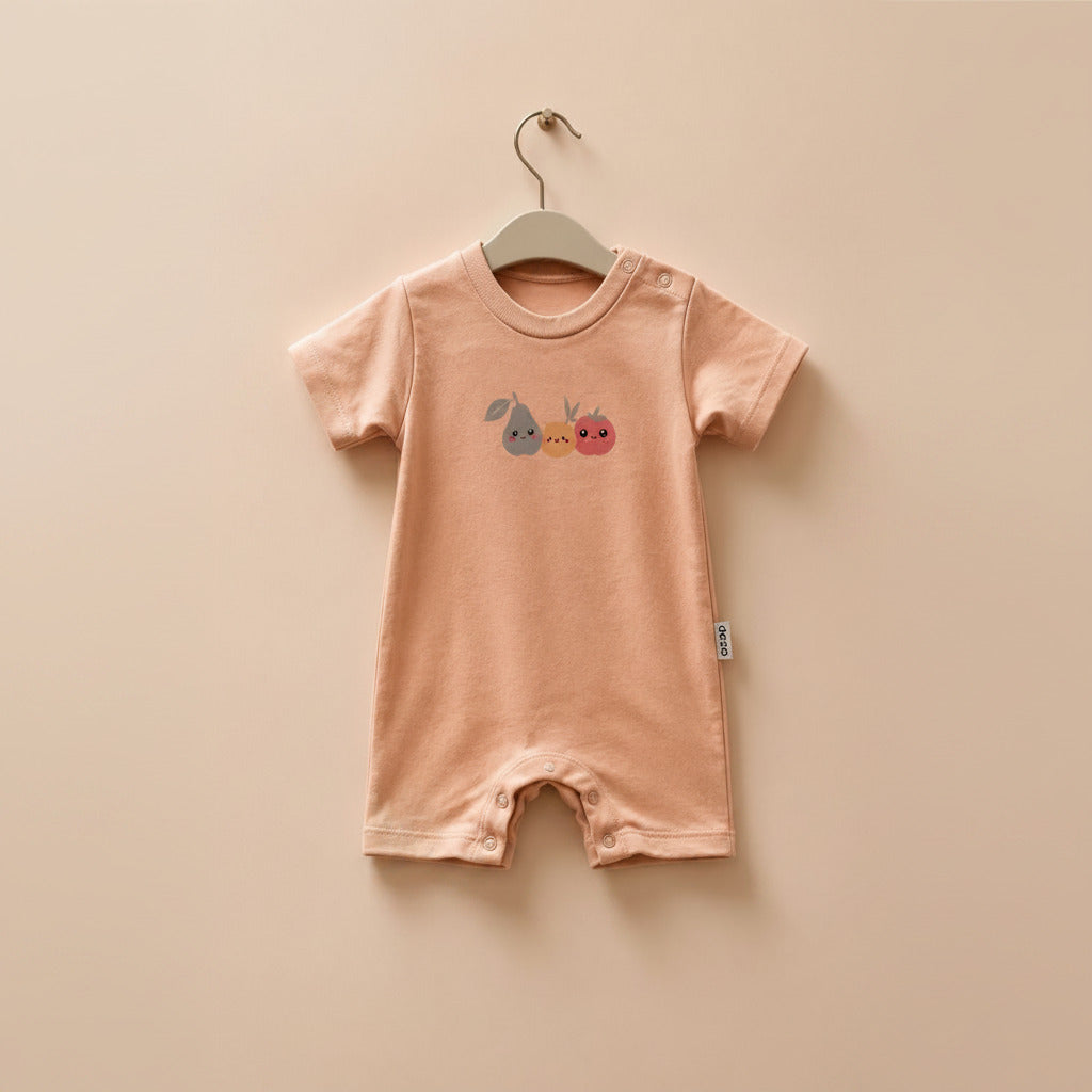 A baby short-sleeve romper in a soft peach-pink color, hanging on a wooden hanger against a matching light beige background. The romper features a small graphic of a blue pear, a yellow bunny, and a red strawberry on the chest.