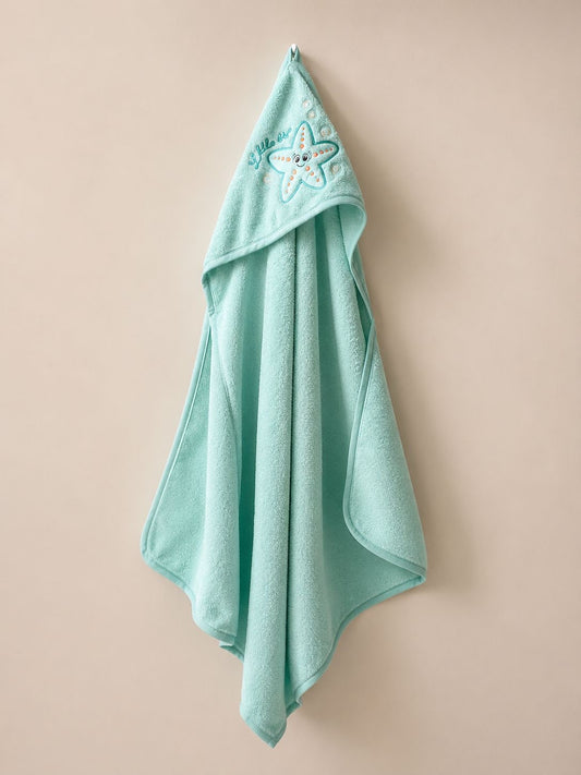 A mint green hooded bath towel with a starfish embroidery on the hood, hanging against a solid beige background.