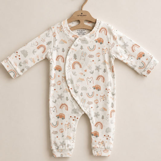 A baby long-sleeve footless romper with an all-over woodland print of rainbows, trees, and animals, hanging on a wooden hanger against a solid beige background.